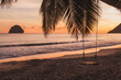 © Anna Berkut/Stocksy - sunset on the beach in Caribbean sea, silhouette of palm tree with rope swing