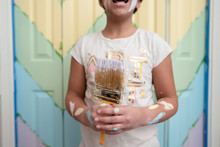 Girl With Paint On Arms Holds Paintbrush