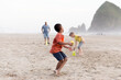 © Jennifer Bogle/Stocksy - Boy throws football on Cannon beach
