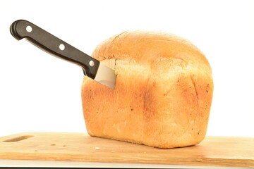 One loaf of flavored wheat bread on a wooden board with a metal knife, close-up, isolated on white.