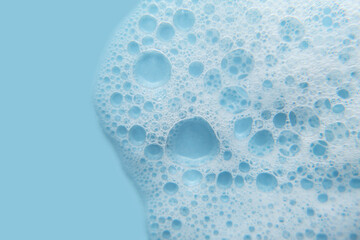 Wall Mural - White cosmetics foam texture on blue background. Cleanser, shampoo bubbles, wash - liquid soap, shower gel, shampoo. Texture of white foam on rose background. Cosmetics banner with copy space.