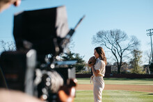 Cinematographer Filming A Female Pitcher On A Baseball Field