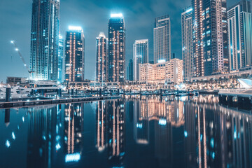 Wall Mural - Hotels and apartment residential skyscraper buildings panoramic view in Dubai Marina Creek Harbour at night with reflections in water