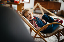 Little Girl Resting In A Vintage Rocking Chair At Home