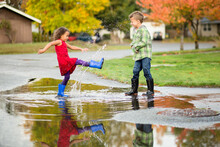 Girl Kicks Water From Puddle At Brother
