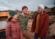 © StratfordProductions - Cheerful young male and female friends in winter clothing laughing during camping on mountain hill