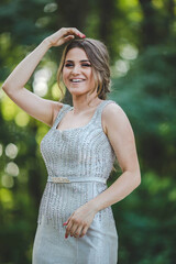 Poster - Pretty Caucasian woman with a silver evening dress and heavy makeup posing in the park