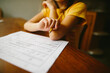 © Maria Manco/Stocksy - Close-up of girl sitting at table at home writing on paper with pencil