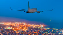 Passengers Airplane Flying Above  City In The Twilight Blue Hour
 - Transportation And Travel