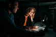 © StratfordProductions - Diverse creative business people working with laptop overtime at night in low light at office
