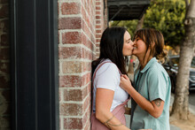 Cute Lesbian Couple Has Fun Kissing One Another Against Brick Wall