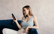 © Sergey Filimonov/Stocksy - Relaxed young lady in true wireless earphones using smartphone on sofa