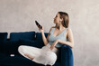 © Sergey Filimonov/Stocksy - Relaxed young lady in true wireless earphones using smartphone on sofa