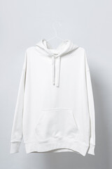 Wall Mural - Blank white hoodie hanging on a hanger against gray background