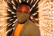 © VICTOR TORRES/Stocksy - Happy black man with protective mask  under bulb lights