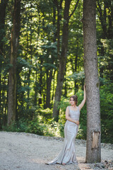 Canvas Print - Pretty Caucasian woman with a silver evening dress posing in the park