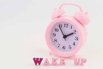 Pink alarm clock and letters wake up on gray background, room for text.