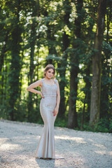 Poster - Vertical shot of an elegant caucasian female in a white evening dress standing on a road