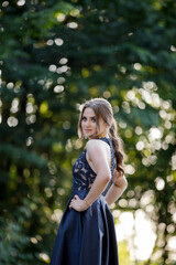 Poster - Pretty Caucasian woman with a dark blue dress and heavy makeup happily posing in the park