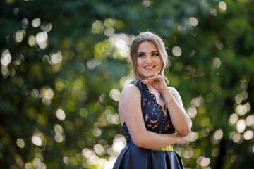 Poster - Pretty Caucasian woman with a dark blue dress and heavy makeup happily posing in the park