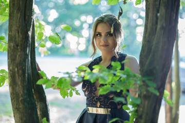 Poster - Sexy Caucasian woman with a dark blue dress and heavy makeup posing in the park