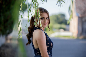 Poster - Attractive Caucasian female wearing an elegant blue dress seen through tree leaves