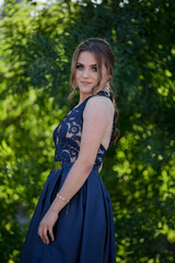 Poster - Attractive Caucasian female wearing an elegant dark blue dress posing in a park