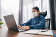 © tong2530 - Asian teen girl wearing headphones learning language online, using laptop, looking at screen, doing school tasks at home, writing notes, listening to lecture or music, distance education