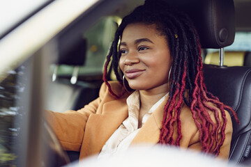 Portrait of positive african american lady inside the car