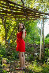 Canvas Print - Pretty Caucasian woman with a red dress happily posing in the park