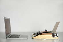 Old Typewriter And Laptop On Table Against Light Background, Space For Text. Concept Of Technology Progress