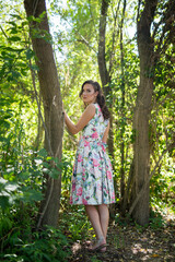 Poster - Beautiful young Caucasian female wearing a floral dress posing on background of a forest