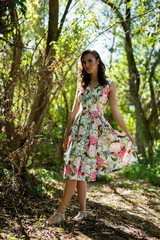 Poster - Vertical shot of a young caucasian female wearing a floral dress in a forest