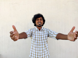 Wall Mural - Smiling attractive Indian man in white shirt stretching his arms, wants to hug you, isolated on white background