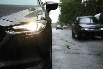 Wall Mural - Modern car on city street, closeup view. Rainy weather