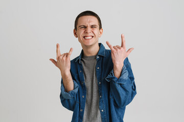 Young brunette man smiling and gesturing horns sign