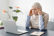 Tired sad exhausted mature islamic muslim businesswoman in hijab tutor online teacher feeling migraine after huge load of a computer working on lockdown. Headache and depression, fatigue concept