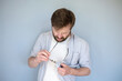 © koldunova - Concentrated Caucasian man cleans glasses from dust and dirt, wiping them with his shirt. Gray background.
