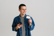 © Drobot Dean - Young white man using cellphone while posing with credit card