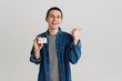© Drobot Dean - Young brunette man pointing finger aside while posing with credit card