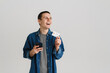 © Drobot Dean - Young white man using cellphone while posing with credit card