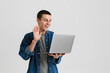 © Drobot Dean - Young brunette man smiling and waving at laptop