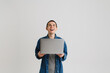 © Drobot Dean - Young brunette man looking upward and holding laptop