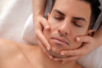 Wall Mural - Man receiving facial massage in beauty salon, top view