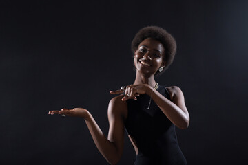 Empty female hand of african american woman holding and pointing on black background