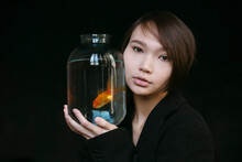 Asian Girl With An Aquarium Fish In A Dark Room.