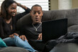 © Sean Locke/Stocksy - Loft: Friends Sit Together On Couch Watching Movie On Laptop