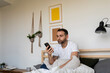 © Valentina Barreto/Stocksy - man browsing mobile phone in bed