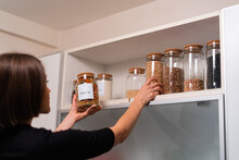Woman Organizing Food In The Kitchen With Glass Containers