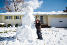 Tall Snowman And Young Boy In Front Of Yellow House